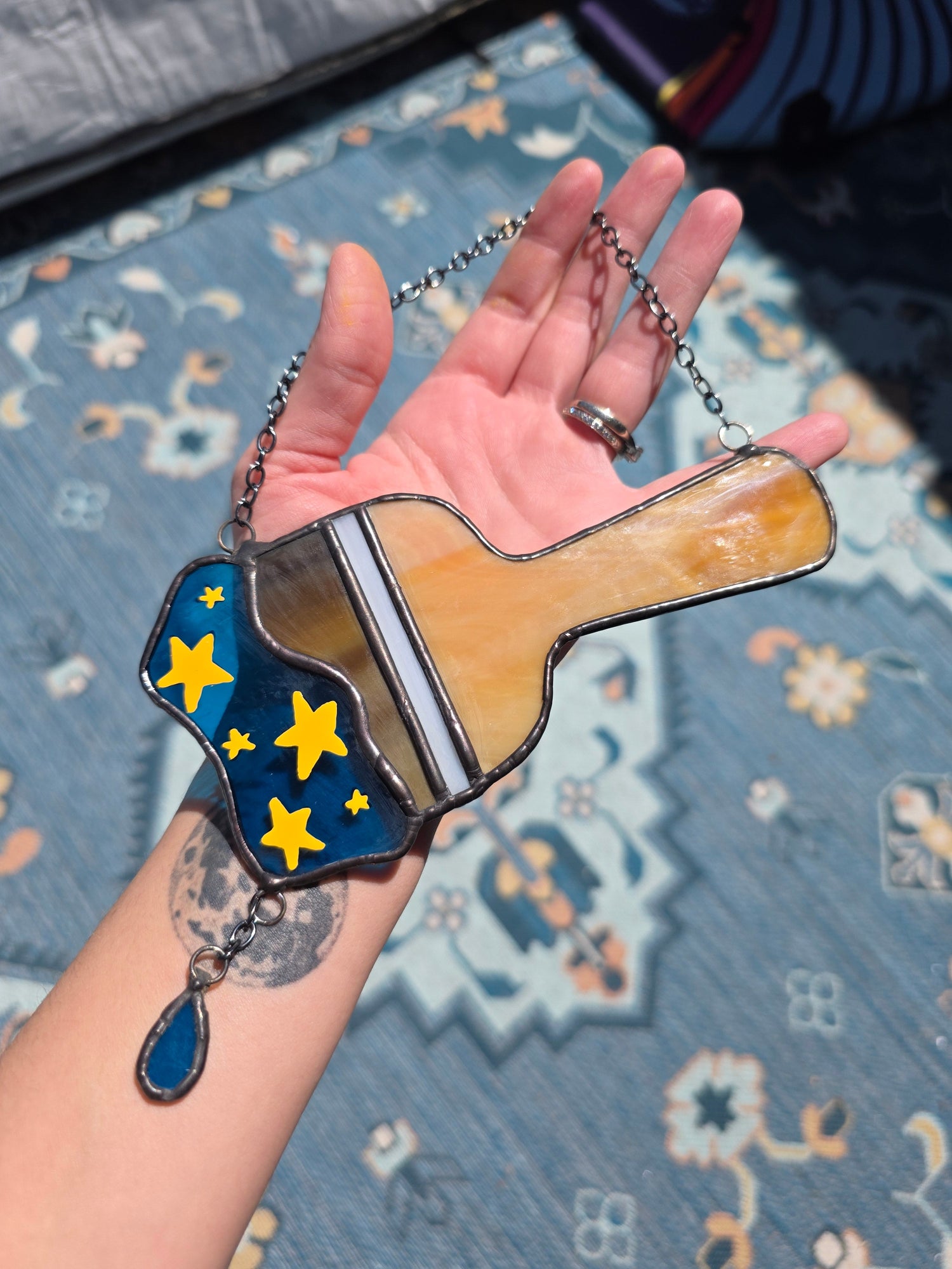 A handmade stained glass Starry Paint Brush from Neopets is being held by the artist.
